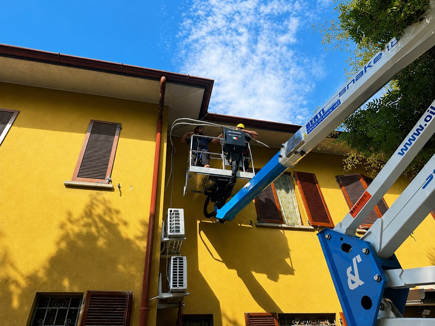 Tecnici AG Termoedile al lavoro su una piattaforma aerea per l'installazione di un impianto sulla facciata di un edificio