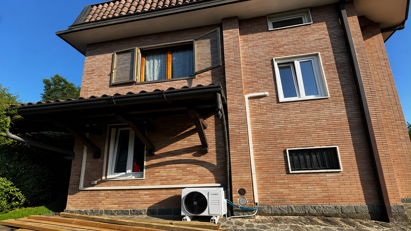 Unità esterna Bosch installata sulla facciata di una villetta in mattoni